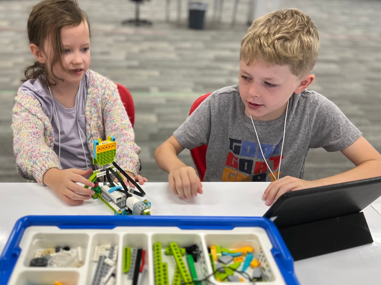 Young kids using elementary programming software to build and code a moving LEGO robot